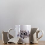 Artistic photo of a broken coffee cup featuring crime-related word art.